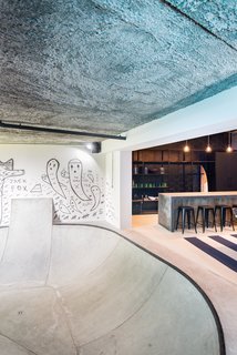 In the adjacent bar, a black Smeg refrigerator and a surfboard rack are just a few inclusions that contribute to the overall industrialized look. Going a step further, a 4.5-meter-long timber bar created from ground and polished concrete was designed to match the flooring. 