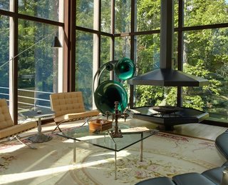 After a Year on the Market, Philip Johnson’s Wiley House Drops by $2 Million - Photo 7 of 9 - Out of the 3,544 square feet of the residence, 1,000 square feet of it comes from the pavilion. The corner of the open living room contains a suspended fireplace, oversized German speakers, and a pair of Barcelona chairs by Ludwig Mies Van Der Rohe. 