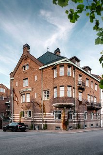 A Visual Journey Through Stockholm's Hotel Ett Hem - Photo 1 of 12 - The street view of the hotel shows its masonry structure and pitched metal roof, which is traditionally seen in Stockholm structures. The solid brick facade acts as a protective shield against Stockholm's bitter winters. 