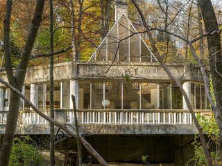 The One-of-a-Kind Home of the Late Architect John Black Lee Drops to $750K - Photo 2 of 10 - Though the house is in need of some dire repairs—including leaks and a lack of heat and water—it stands proud with its original architecture built entirely of concrete and glass. It cantilevers over the Silvermine River. 