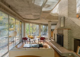 The One-of-a-Kind Home of the Late Architect John Black Lee Drops to $750K - Photo 5 of 10 - The living spaces and dining room are connected and feature an original fireplace. The concrete foundation is exposed throughout, accentuating the house's angular lines. 
