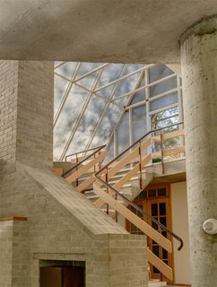 The One-of-a-Kind Home of the Late Architect John Black Lee Drops to $750K - Photo 6 of 10 - Wood-and-metal stairs lead up from the living space to the skylight entrance. The glass A-frame gives the feeling of a greenhouse or garden shed. 