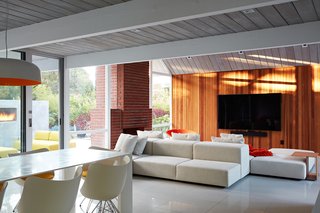 To satisfy the couple’s desire to combine the kitchen, living, and dining spaces into one large area, they removed any barriers and installed walnut vanities and cabinets for extra storage. They preserved the original brick fireplace. 