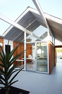 As one of Eichler’s courtyard models, the home's office looks directly through the atrium and into the glass-enclosed living room, providing the ultimate indoor/outdoor feeling. The gray porcelain tile that Klopf Architecture installed in the interior is continued into the atrium. 