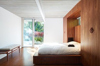 To enlarge the bathroom, they combined it with the master bedroom's closet—and thus had to create new storage. So, they designed a custom walnut bed wall that contains built-in wardrobes. 