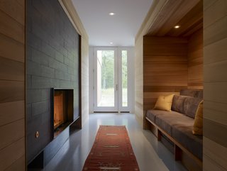 Entering through the front door leads you to an inglenook, where Lynch installed a fireplace and a custom built-in seating area that’s surrounded by red cedar. 