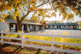Modern Equestrians Will Find Themselves at Home at This New Americana Hotel - Photo 1 of 7 - The white board-and-batten facade takes cues from the surrounding stables and is surrounded by billowing grass and birch trees. 