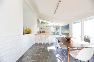 If You Crave Bright, Light-Filled Spaces, This Midcentury Home For Sale Could Be the One - Photo 3 of 9 - Though the main bones have been kept intact, one of the past owners installed slate flooring in the entryway, hallway, and dining area (shown here)—which leads into the lengthy kitchen. 