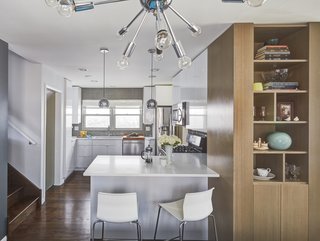 To create a better flow, they took out the wall between the kitchen and dining rooms and added a peninsula where they could put bar stools for people to hang out while they’re cooking. They also moved the range closer to the peninsula to create a better layout for entertaining. Finally, they installed new quartz countertops and fresh cabinets. They salvaged some of the old cabinets and repurposed them in the laundry room downstairs. 