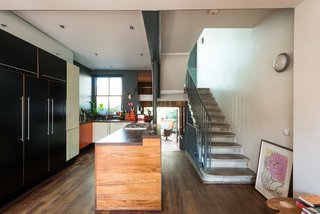 On the other end of the dining space is the kitchen, which contains an extensive island that acts as a divider from the pathway that leads to the garden room. One of the many sets of original concrete stairs is seen on the right. 