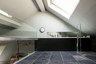 When you climb the spiral stairs, you’re led to the en-suite bathroom on the mezzanine level, which revels in natural light—thanks to a substantial angled skylight above, 