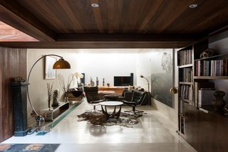 Once you enter, a hallway leads you into a reception/living area with polished-concrete floors and paneled walls that are partly lined with iroko wood. A double-height section lets in slices of light from the galleried garden room above.