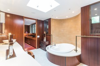 Frank Lloyd Wright’s Last Major Residential Masterpiece Could Be Yours for $8 Million - Photo 7 of 11 - Shown here is one of the double master bathrooms, which holds a new tub that sits in front of a painted plaster wall. The layout and mahogany panels have remained original. 