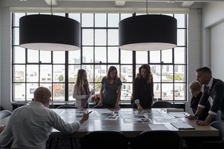 A San Francisco Design Collective Reveals its Impeccably Cool Creative Studio - Photo 5 of 12 - In the main conference room, Hollis and a few members of her team spread out photos and plans over a custom conference table made Christian Hummler. The pendants overhead are designed by Piet Boon for Moooi.