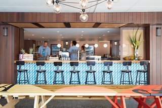 This Surf-Inspired Hotel Celebrates Waikiki’s Creative Spirit and its Midcentury Roots - Photo 5 of 13 - At Mahina & Sun’s, chef Ed Kenney believes in, "local first; organic whenever possible; with aloha always." The picnic tables next to the bar were hand-painted by local artist Jeff Gress.