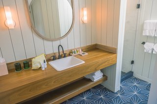 This Surf-Inspired Hotel Celebrates Waikiki’s Creative Spirit and its Midcentury Roots - Photo 12 of 13 - The bathrooms boast custom ceramic floor tiles and an organic-feeling stone flooring in the shower. Andrew Mau, who designed the shaka wallpaper in Mahina & Sun's, also created the Moana Vanity Mirrors.