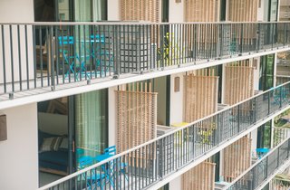 This Surf-Inspired Hotel Celebrates Waikiki’s Creative Spirit and its Midcentury Roots - Photo 13 of 13 - On each of the 10 floors, the balcony rooms have private lanais that are divided by woven screens for privacy. While sitting on the brightly-hued outdoor chairs, you’ll look out to other midcentury buildings while planning your tropical adventure ahead. 