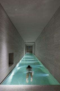 10 Exquisitely Modern Homes in Italy - Photo 6 of 10 - And even in areas where the light is a more pragmatic tool, it is integrated wonderfully, as in the long indoor pool and in the minimally modern bathroom. Each light feels like an architecture in and of itself, dancing through the home in a game of reflection and feedback. So while the home stands proudly during the day, it is at night that its true nature comes to light. 