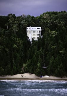 Nestled into a steeply sloped waterfront site on Lake Michigan, the all-white, starkly modernist home is defined by verticality. 