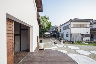 7 Warehouse Conversions: Turning Industrial Buildings Into Modern Commercial Spaces - Photo 4 of 13 - New circular plinths, a nod to stepping stones found in Japanese gardens, surround the structure to activate the vacant areas of the building lot. Extending to the outdoors, the stage invites engagement from passersby.