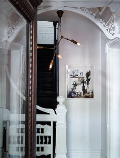 Carefully placed modern touches illuminate restored details in the home. An industrial-style pendant, which Jeff and Jason made themselves using a DIY instructional kit by lighting designer Lindsey Adelman, hangs from the intricate millwork in the entryway. The print is by photographer Anna Wolf.