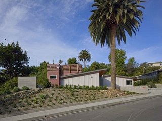 A Mid-Century Modern Makeover in Los Angeles - Photo 5 of 5 - A view of the completed renovation; from the street, the open amphitheater-style courtyard appears as a simple wooden addition, privately tucked away. Wood slats, exterior cladding, and the new trellis all combine to form a linear motif.
