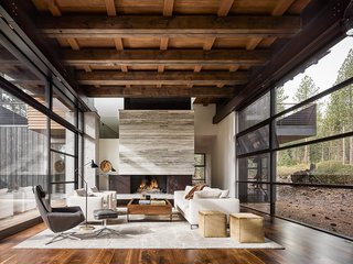 A Family's California Ski Retreat is Designed to Blend in With Its Site - Photo 2 of 5 - The 5,700-square-foot getaway features glazed screens surrounding the living and dining areas. A travertine marble slab fireplace anchors the space; the floors are California walnut.