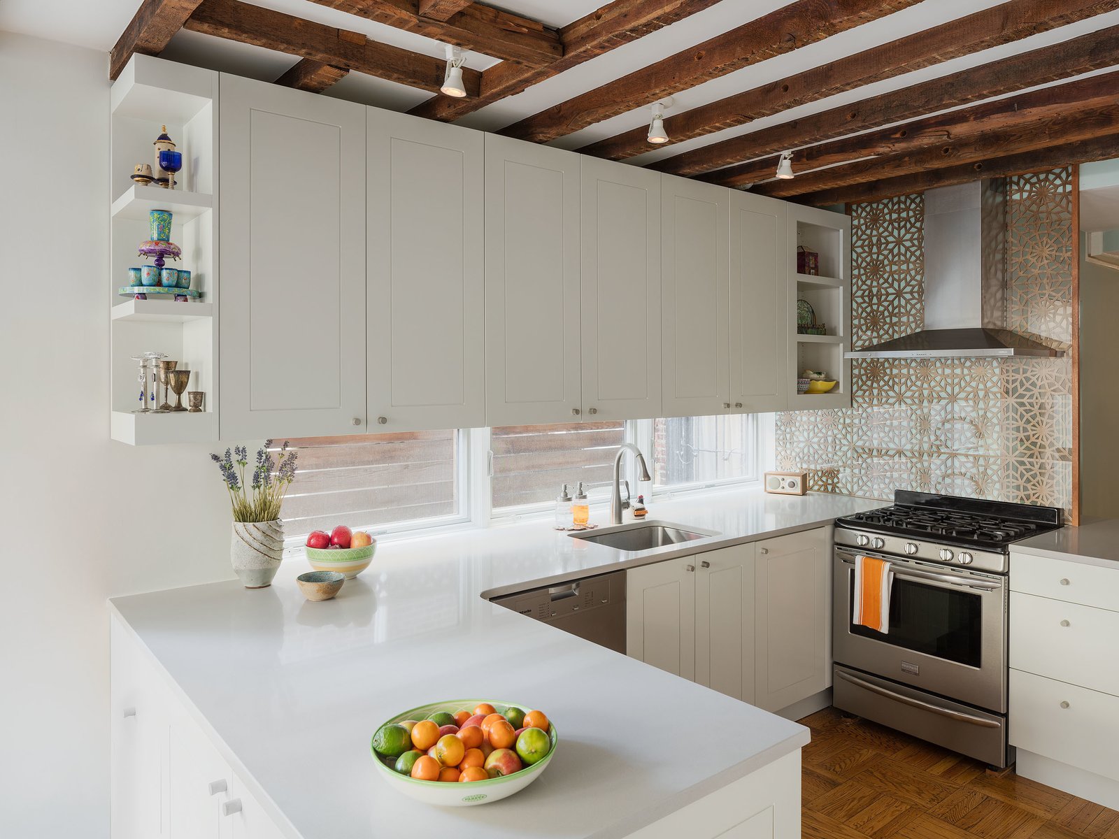 Philadelphia Row House Renovation - Photo 3 of 8 - A bright new kitchen is the highlight of the renovation. The pattern behind the stove call to mind traditional Persian motifs. A row of windows provides a light-filled alternative to a backsplash behind the sink.