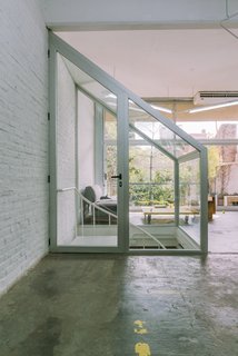 Factory Renovation in Buenos Aires Fights for Natural Light - Photo 1 of 2 - Brazilian architecture firm Pop-Arq flipped a dark industrial space in Buenos Aires into a bright split-level office for motion graphics studio ELOISA. A new glass enclosure for an existing spiral staircase provides acoustic insulation and a dimension of privacy without blocking light from the floor-to-ceiling windows. 