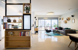 A Riotous Makeover for a Generic High-Rise Home - Photo 1 of 3 - The 1,400-square-foot apartment, located in in a 21-floor high-rise, features a custom shelving unit/room divider by Greenbox Studio, which separates the living area and kitchen. 