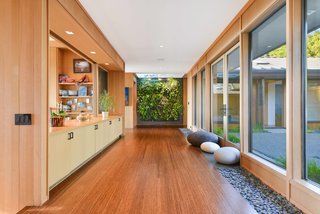 The Mexican river rocks that hardscape the outdoors continue in the interior hallway, which connects the bedroom and living spaces. The green wall system is by Woolly Pocket. The flooring is Ecotimber strand-woven bamboo. 