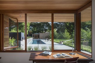 Channeling Midcentury Modern in Northern California - Photo 3 of 7 - Looking out from one of the home offices, a board-formed concrete garden wall and linear pool draw the eye toward a guesthouse. 
