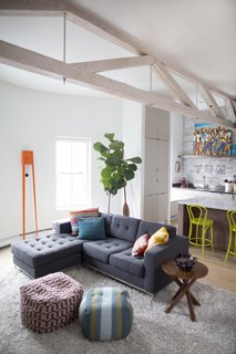 This Modern Boston Renovation Expertly Mixes in Colorful Craft Finds - Photo 2 of 4 - The living room features an eye-catching Tiuku grandfather clock by Covo. The Gus sofa is from Lekker. The flooring is new. 