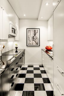 The 650-square-foot apartment has a galley kitchen with checkered black-and-white tile. 