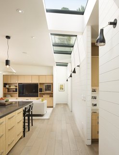 A painted wood wall marks the boundary between the home’s public and private wings. Linear skylights bathe the open-plan communal area in light. 