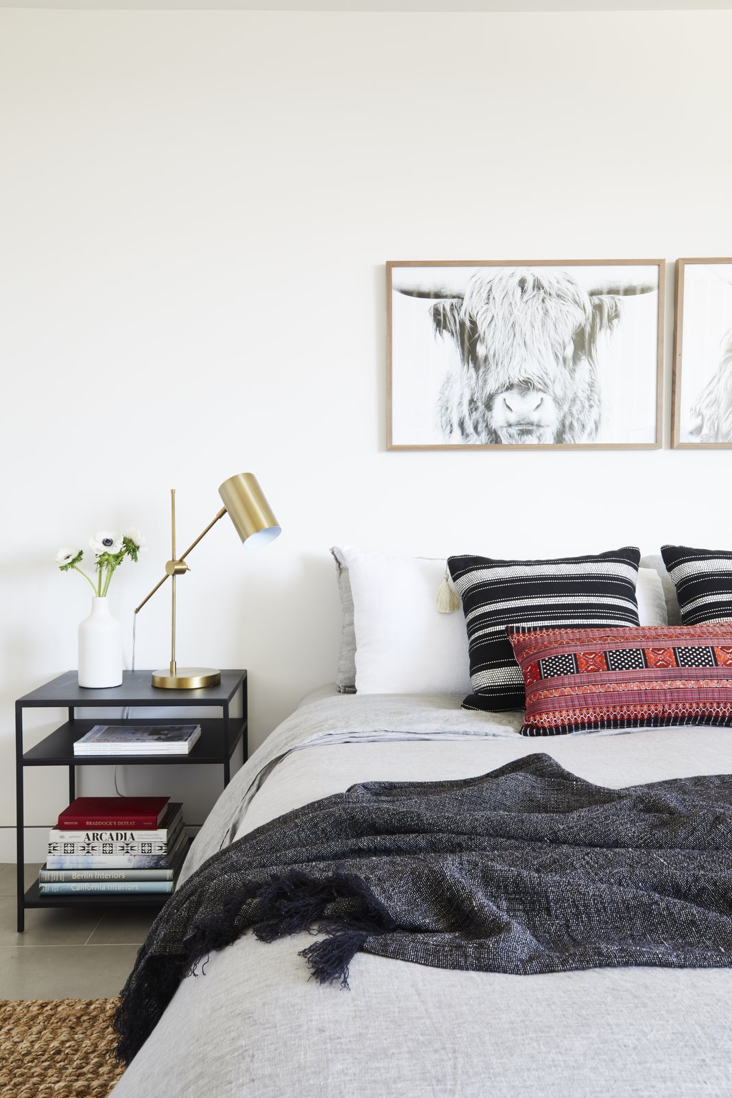 A Tim Gainey photograph of a Highland cow from Fine Art America sits above a red lumbar pillow by Amber Interiors and Restoration Hardware Bedding.