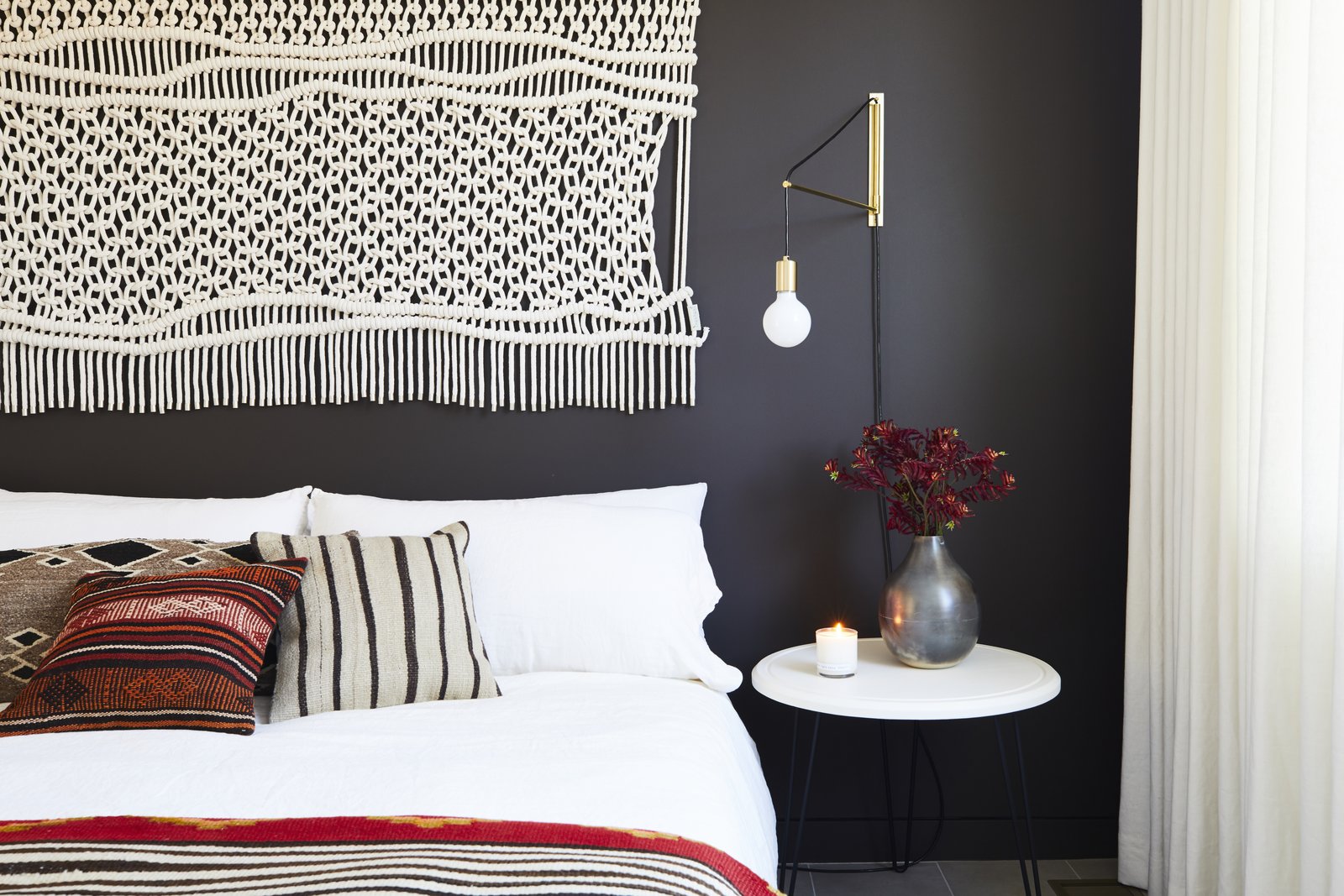 In the second bedroom, a macrame wall hanging and gold sconce were found at Etsy, which matches the sentiment of the DIY nightstand. Matteo bedding pops against the