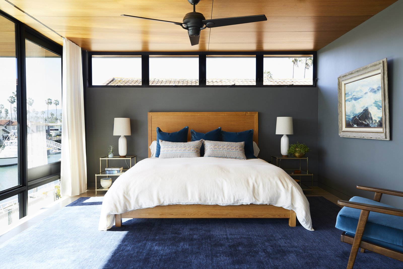 The master bedroom unites the rest of the home's shades and textures in a calm palette. The custom bed is centered above a Crate and Barrel area rug. As with most of the art in the home, the one hanging here on Benjamin Moore's