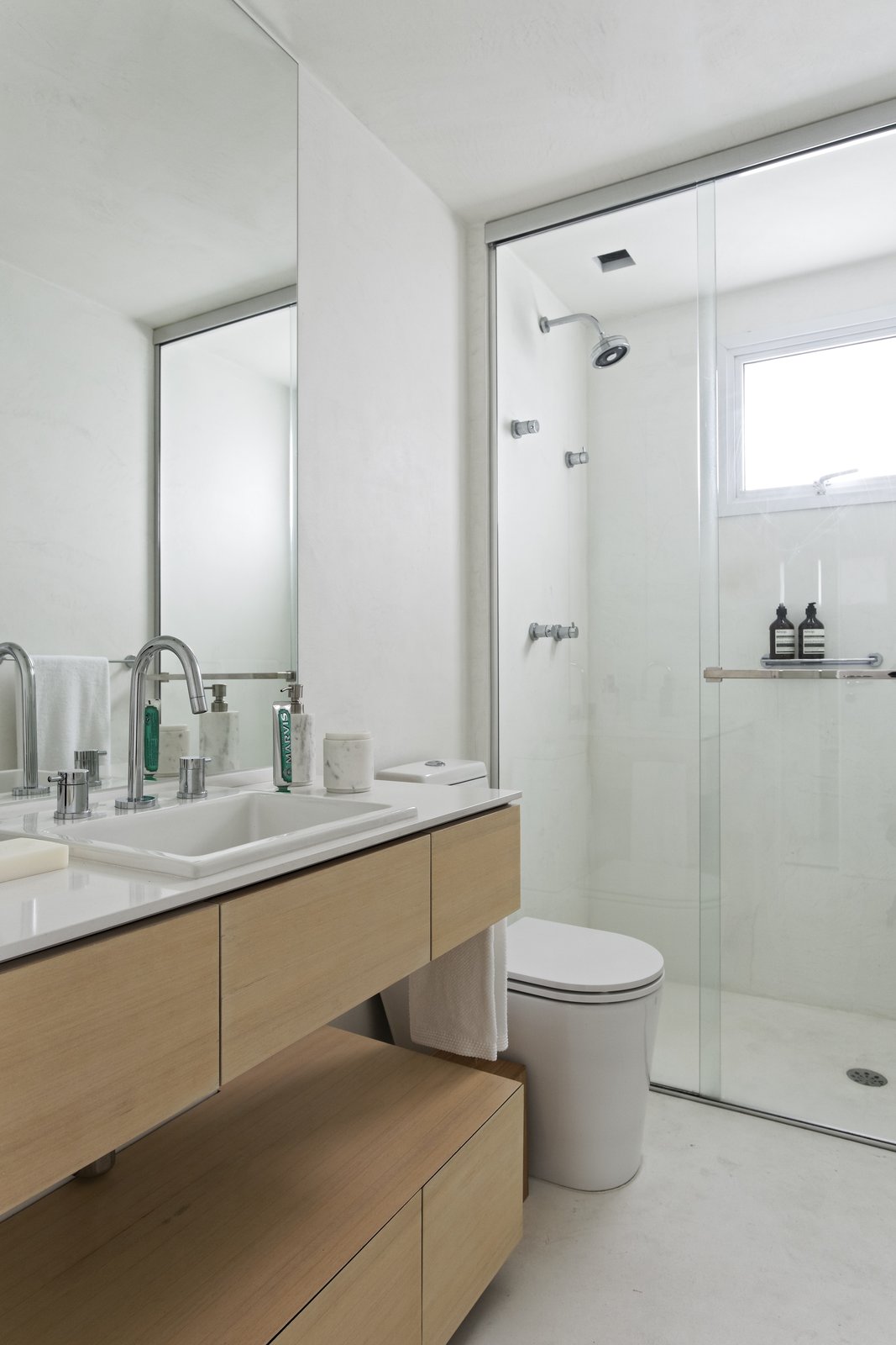 A Brazilian Bachelor Pad Embraces Light and Darkness The main bathroom is unified with the rest of the home thanks to the same burnt cement flooring. A solid wood countertop was installed by Inovart Woodworking, and the adjoining white quartz countertop was picked from MSA Marmoraria.