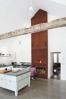 A Cor-Ten steel panel tower that's been acid-oxodized and weathered over three years houses a wood-burning pizza oven at its base.