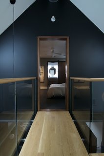 10 Bright and Airy Modern Attic Renovations - Photo 4 of 10 - A catwalk runs between the guest and master bedrooms in this attic renovation. The white oak floors help the new attic level blend with the rest of the house.