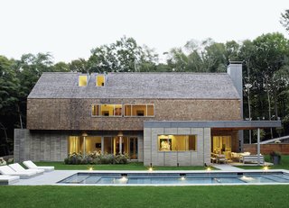 The gabled house, constructed from precast-concrete panels by Superior Walls with wood framing, offers a pared-down version of a traditional New England silhouette. The exterior cedar paneling also appears on the ceiling of the custom-built chef’s kitchen inside.