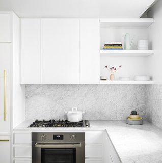 Formerly Home to Superman, The Standish Offers Modernized Beaux-Arts Condos From $1.3 Million - Photo 4 of 8 - The white minimalist kitchen is fully outfitted with premium Bertazzoni Italia and Bosch appliances. It also features Italian Cararra marble countertops, an island, custom-designed cabinetry, and natural brass Fantini fixtures. 