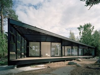 A Look at 10 Minimalist Scandinavian Cabins - Photo 5 of 10 - A light-weight building in glass and wood, this summer house in the Stockholm archipelago has been inspired by its location. A dark wood exterior, strong vertical presence, and abundance of windows help integrate the residence into its surrounding environment. <span style="color: rgb(204, 204, 204); font-size: 13px;">Tham & Videgard Hansson Arkitekter</span>