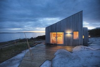 A Look at 10 Minimalist Scandinavian Cabins - Photo 6 of 10 - Designed by TYIN tegnestue Architects and built by the owners themselves, this cottage celebrates traditional back-to-nature elements in traditional Norwegian culture. Situated amidst marshland, sea-adjacent rock, and scattered pine-and-juniper vegetation, careful consideration was made to protect the sensitive surrounding terrain. Only 328 feet from the sea, some marsh had to be cleared while preparing for the construction, exposing bedrock—which integrated the cottage into the landscape.