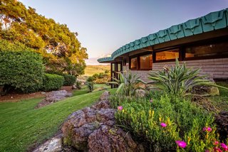 10 Frank Lloyd Wright Homes Available to Rent Right Now - Photo 6 of 10 - The only Frank Lloyd Wright-designed home in Hawaii captures not only the architect's signature style, but also the spirit of its location—with an outdoor lava-rock hot tub overlooking the ocean and breathtaking, panoramic mountain views of three of the Big Island’s awe-inspiring volcanoes (Mauna Kea, Mauna Loa, and Hualalai). The 1995 home was commissioned by Sanderson Sims in partnership with Taliesin Associated Architects, John Rattenbury, and the Frank Lloyd Wright Foundation. Originally conceived for the Cornwell Family in Pennsylvania in 1954, the 3,700-square-foot passive solar hemicycle home embodies the architect's principles of organic architecture in which the structure blends harmoniously with the natural landscape. 