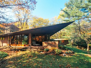 10 Frank Lloyd Wright Homes Available to Rent Right Now - Photo 3 of 10 - The Palmer House was built for William and Mary Palmer in Ann Arbor during the early 1950s, and is one of Wright's last residential masterpieces. Completely secluded and nestled against the northeast side of the beautiful Nichols Arboretum, the house is only a five minute drive (or twenty minute walk) to downtown Ann Arbor—home of the University of Michigan.<br><br>The 2,000-square-foot home is furnished with a collection of Wright-designed furniture and even includes a teahouse. The signature Wright design complements the sylvan setting with bold triangular geometry and a cantilevered overhang.