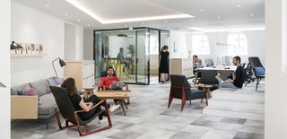 Take a Peek Inside Airbnb's New Loft-Inspired Office Space in Paris - Photo 6 of 13 - Designed for 60 employees, the office provides various work configurations and spaces that include sit-stand desks, private phone booths, and a hospitality lounge. All of the spaces are configured for communal working and employees can sit at large custom-designed tables. This facilitates interaction in a way that individual desks cannot.