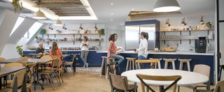 Take a Peek Inside Airbnb's New Loft-Inspired Office Space in Paris - Photo 11 of 13 - The "cuisine" is the heart and soul of the Paris office. It's a communal space for gathering that helps employees stay connected, building on local traditions where staff members eat together everyday. This creates a genuine sense of family and home in the workspace. During construction, the team discovered existing skylights and original wood beams, which they were able to expose and incorporate into the new design to offer a more open and airy kitchen space.