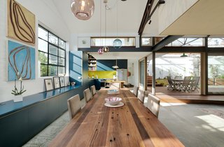 A 1960s Melbourne Warehouse Is Upcycled and Transformed Into an Energy-Efficient Family Home - Photo 8 of 11 - Custom cabinetry lines the dining area, which is defined by a large wood dining table and colorful glass pendant lights.